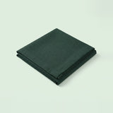 A folded dark forest green fabric item, likely a napkin or cloth, shown on a clean, solid, very light off-white background.
