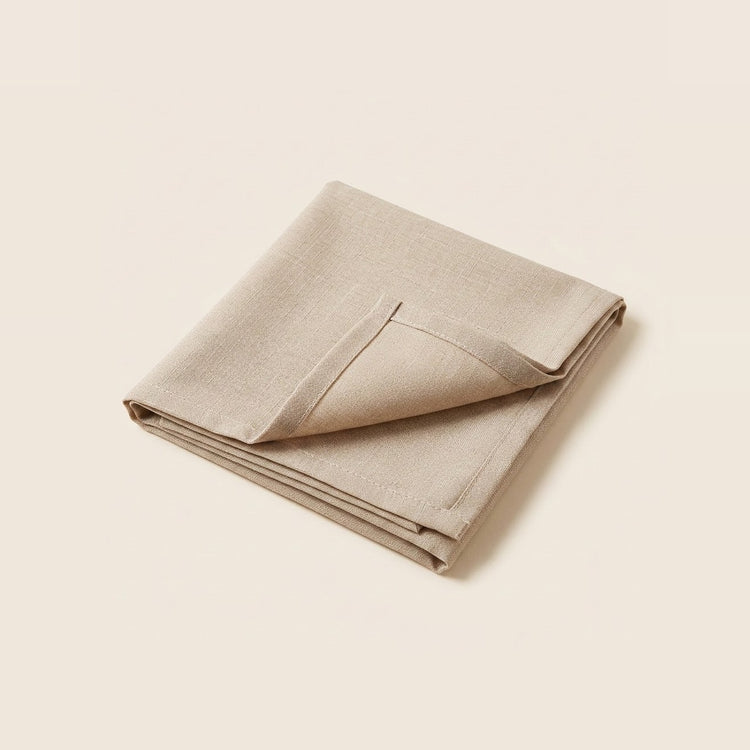 A folded beige linen napkin with a small pocket, displayed on a solid cream background.