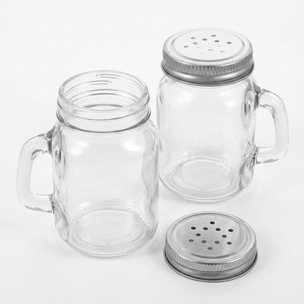 Two clear glass mason jar mugs with side handles and silver metal shaker lids, shown on a clean white background.