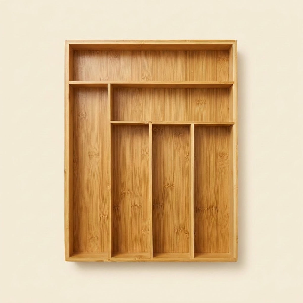 A rectangular bamboo organizer tray with multiple compartments, shown against a solid light beige background.