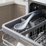 A close-up of a dishwasher's interior with the lower rack pulled out, showing a speckled gray and white ceramic spoon resting in the rack.