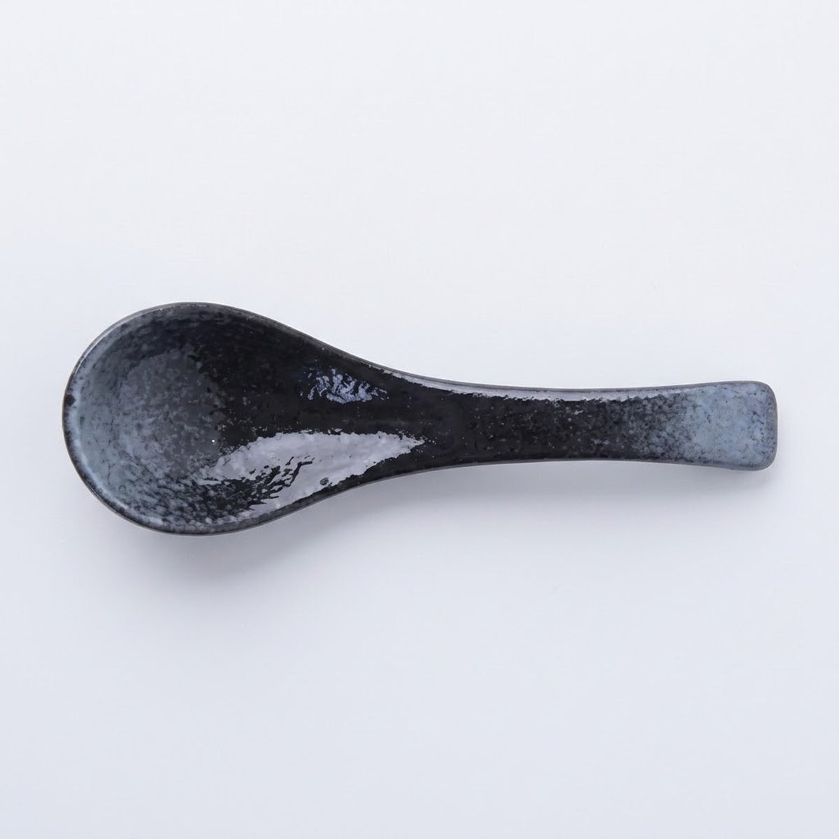 A single dark ceramic spoon with a textured, speckled black and gray glaze, photographed on a clean white background.