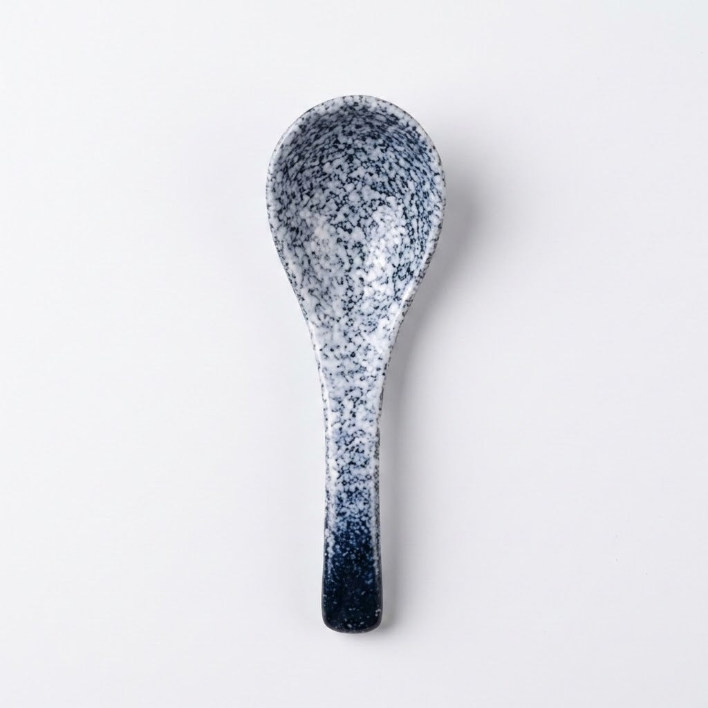 A ceramic spoon with a speckled navy blue and white glaze, shown vertically against a plain white background.