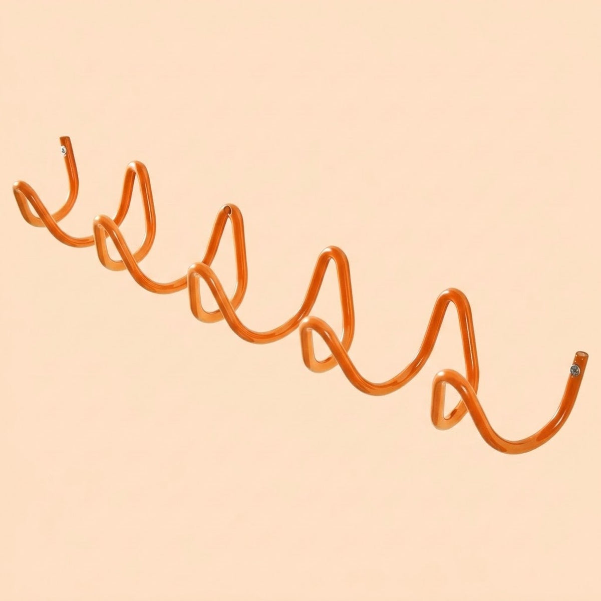 An orange spiral-shaped wall hook mounted on a solid pale peach background.