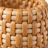 Macro detail shows the smooth honey-colored rattan strands and tight weave of the napkin ring.