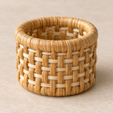 A natural tan rattan napkin ring displays its sturdy rounded rim and tight basket weave in soft light.