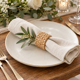 A natural tan rattan napkin ring holds a cream napkin at an elegant rustic wedding place setting.
