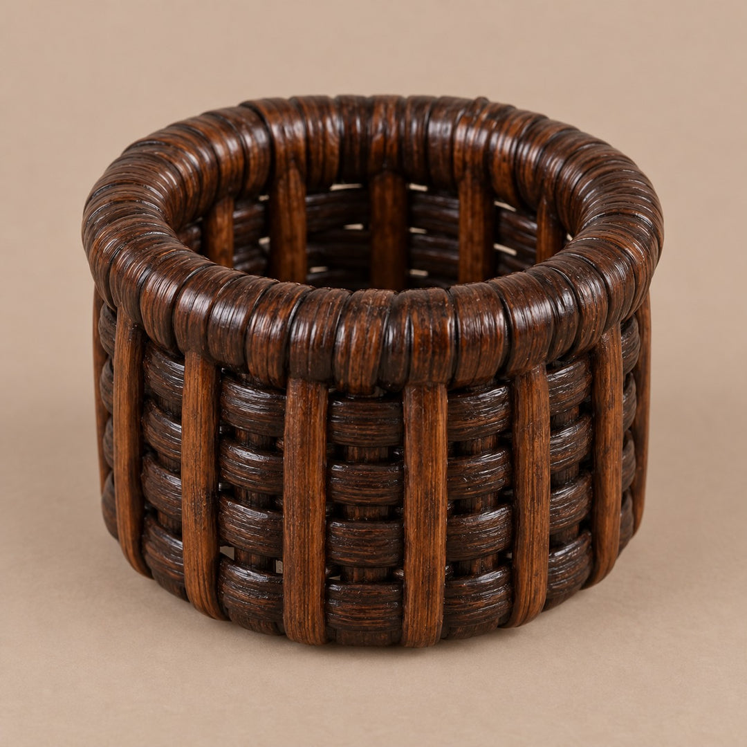 Dark brown basket-weave rattan napkin ring centered on a muted cocoa studio backdrop.