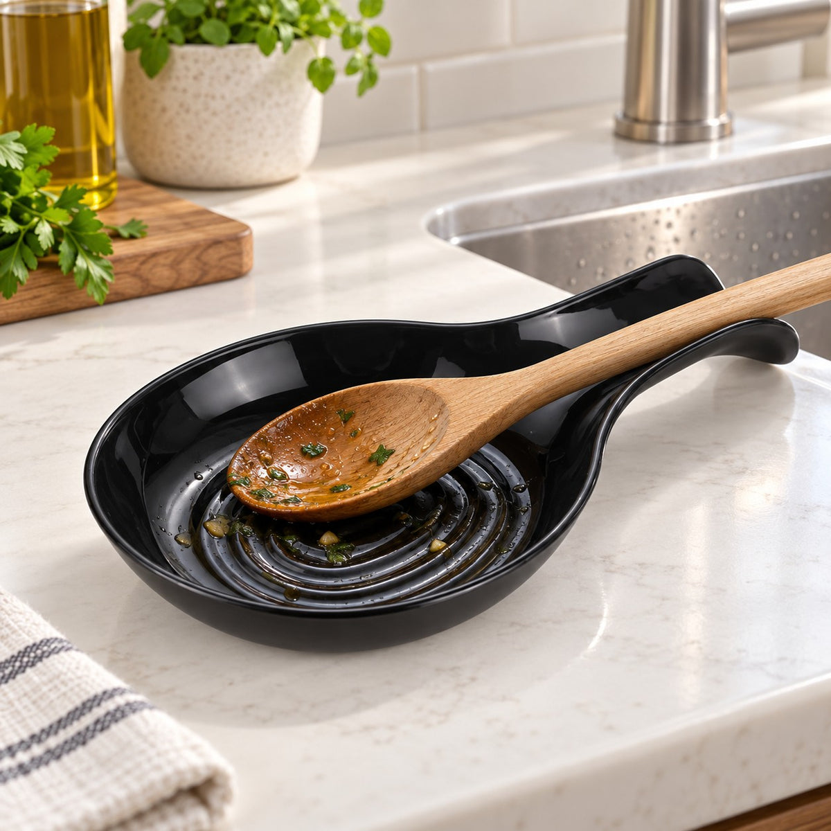 A black spoon rest holds a rinsed cooking spoon beside a bright kitchen sink.