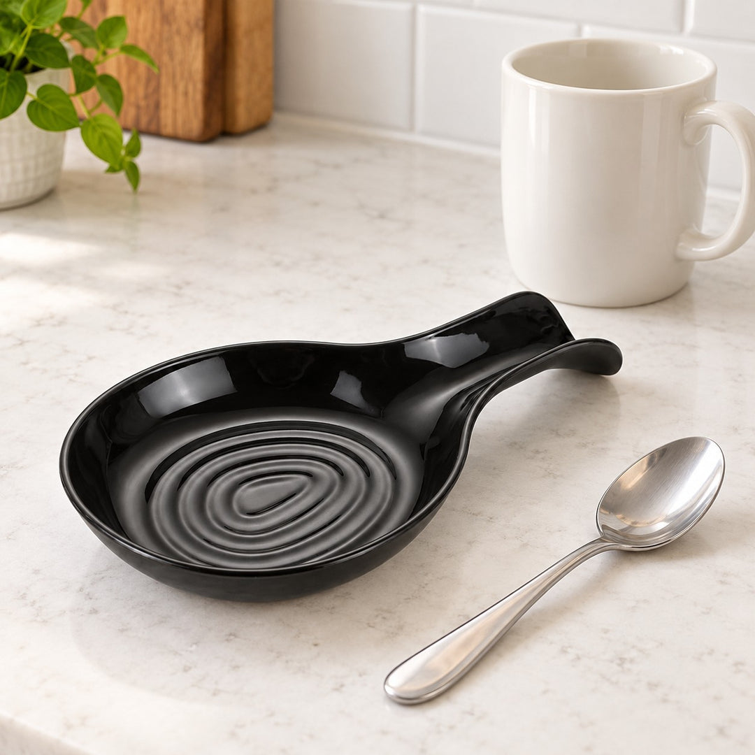 Black plastic spoon rest shown beside a stainless teaspoon and ceramic mug for scale.