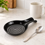 Black plastic spoon rest shown beside a stainless teaspoon and ceramic mug for scale.