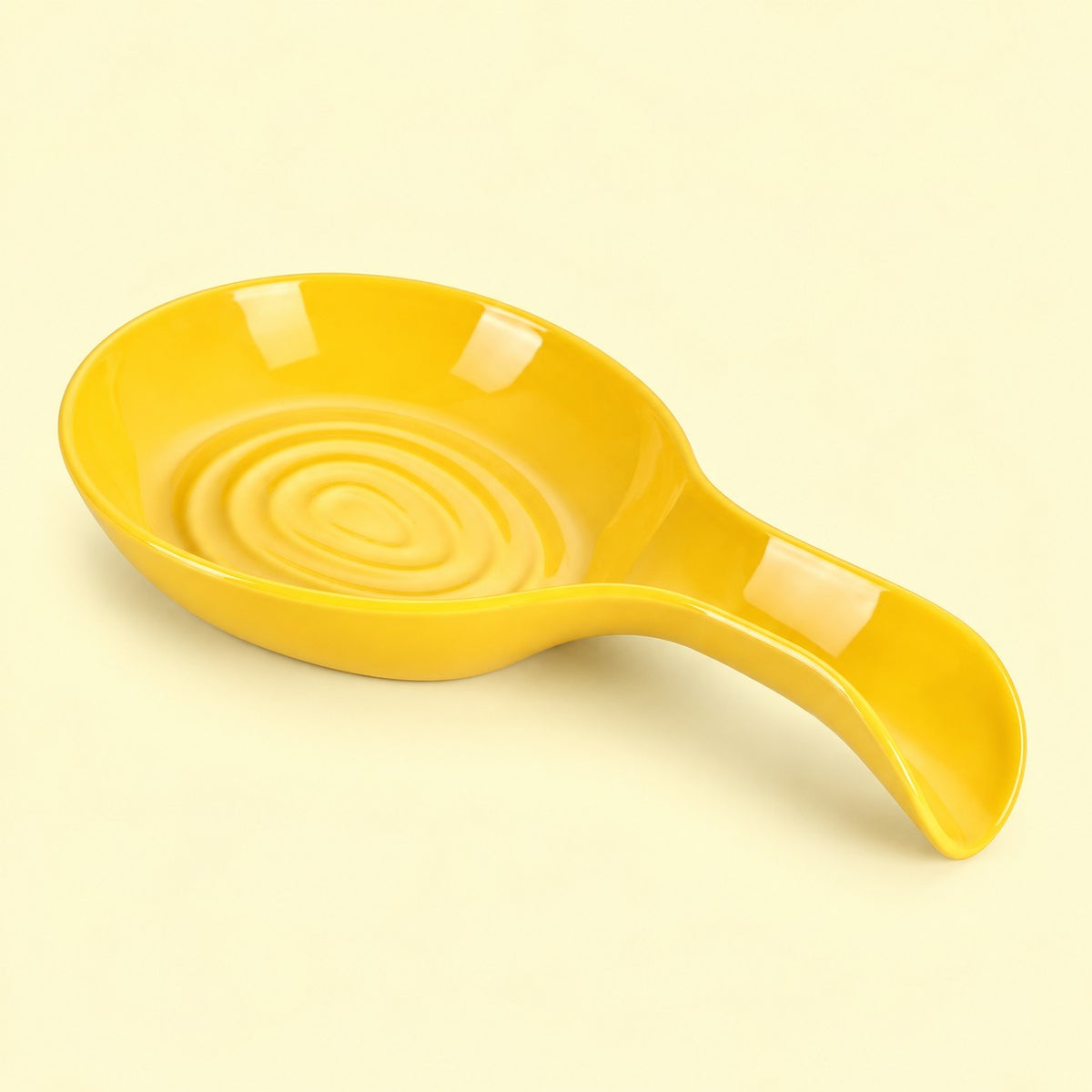 Yellow plastic spoon rest with an oval grooved bowl on a pale yellow backdrop.