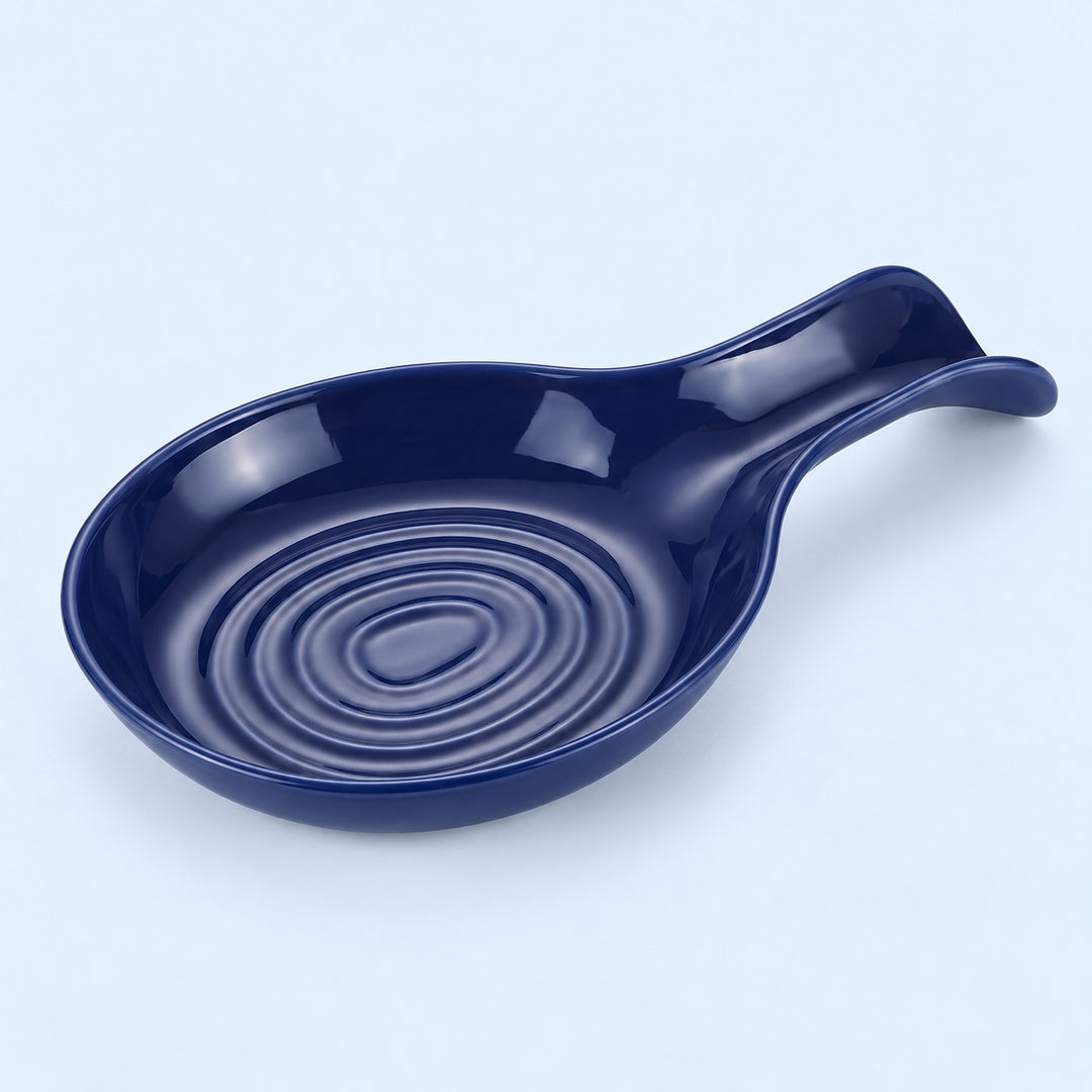 Dark blue plastic spoon rest with raised bowl grooves on a pale blue backdrop.