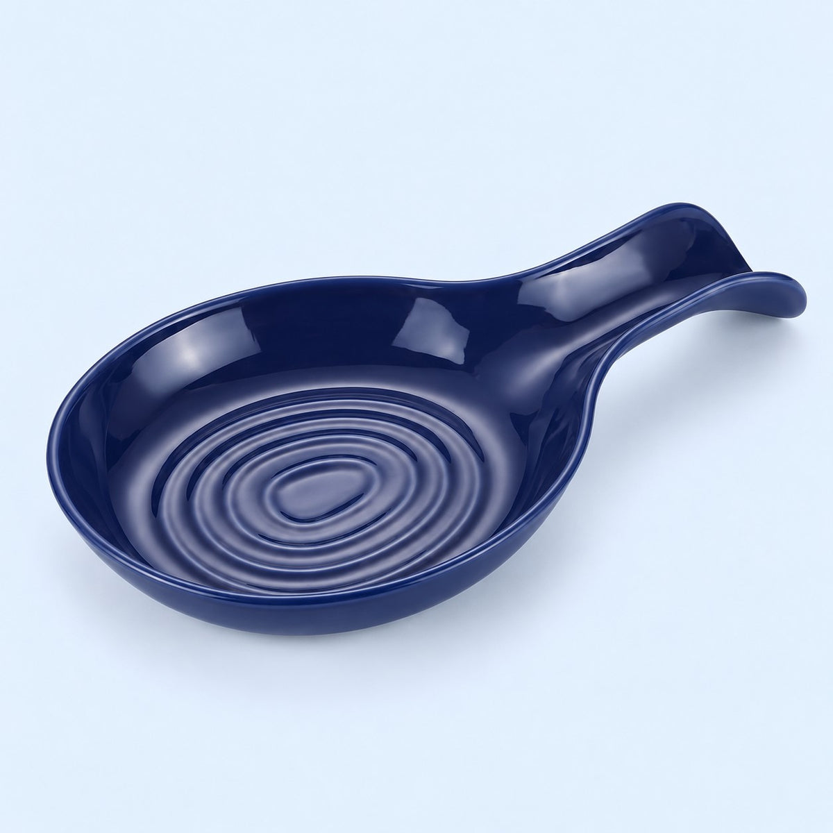 Dark blue plastic spoon rest with raised bowl grooves on a pale blue backdrop.