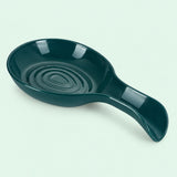 Dark green plastic spoon rest with a curved handle on a pale mint backdrop.