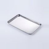 A rectangular stainless steel tray with raised edges, shown at an angle on a clean white background.