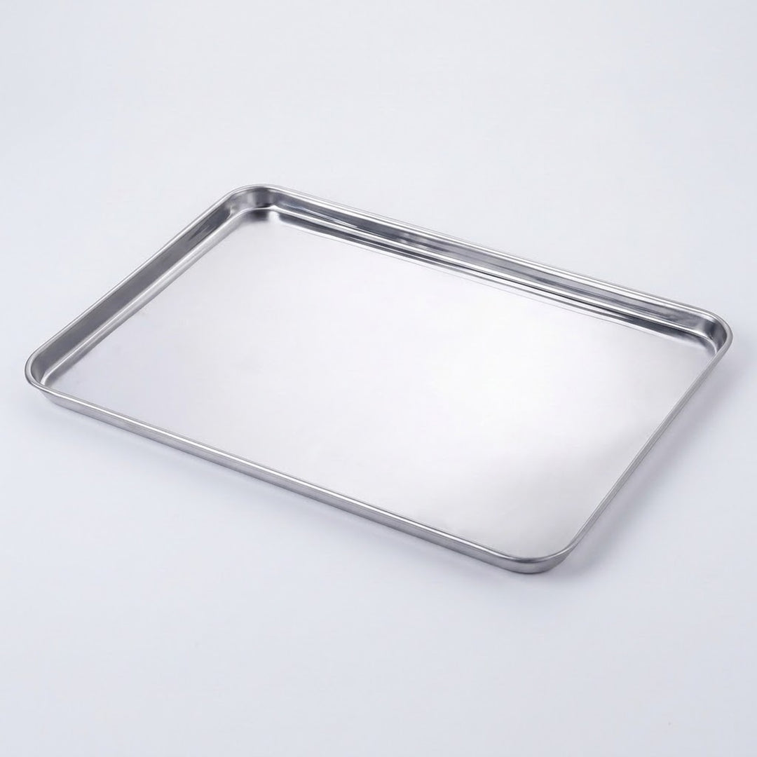 A rectangular stainless steel baking pan with raised metal rims, photographed on a clean white background.