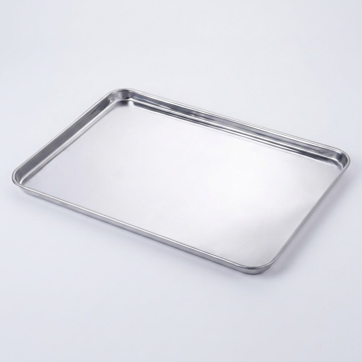 A rectangular stainless steel baking pan with raised metal rims, photographed on a clean white background.
