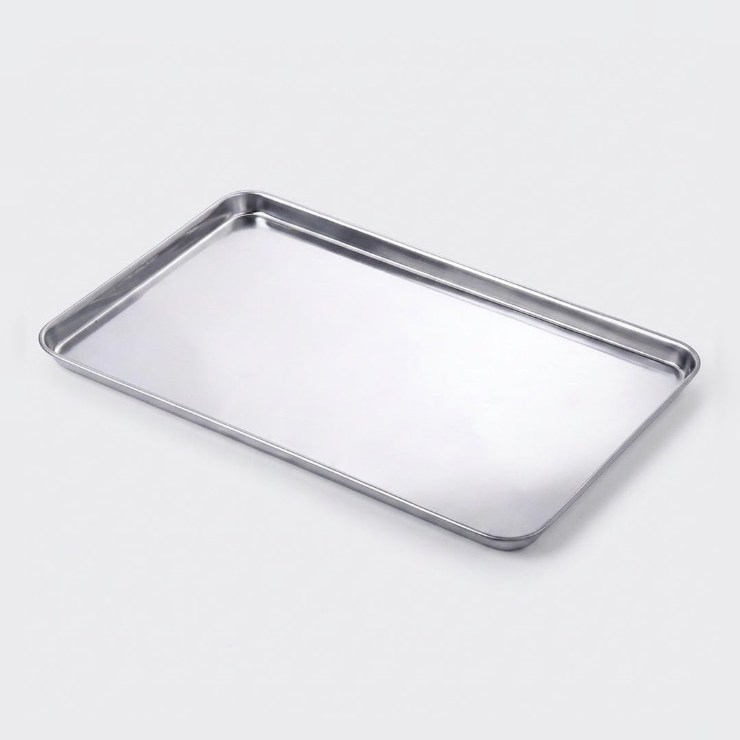 A rectangular stainless steel baking tray with raised edges, shown at an angle on a light gray background.