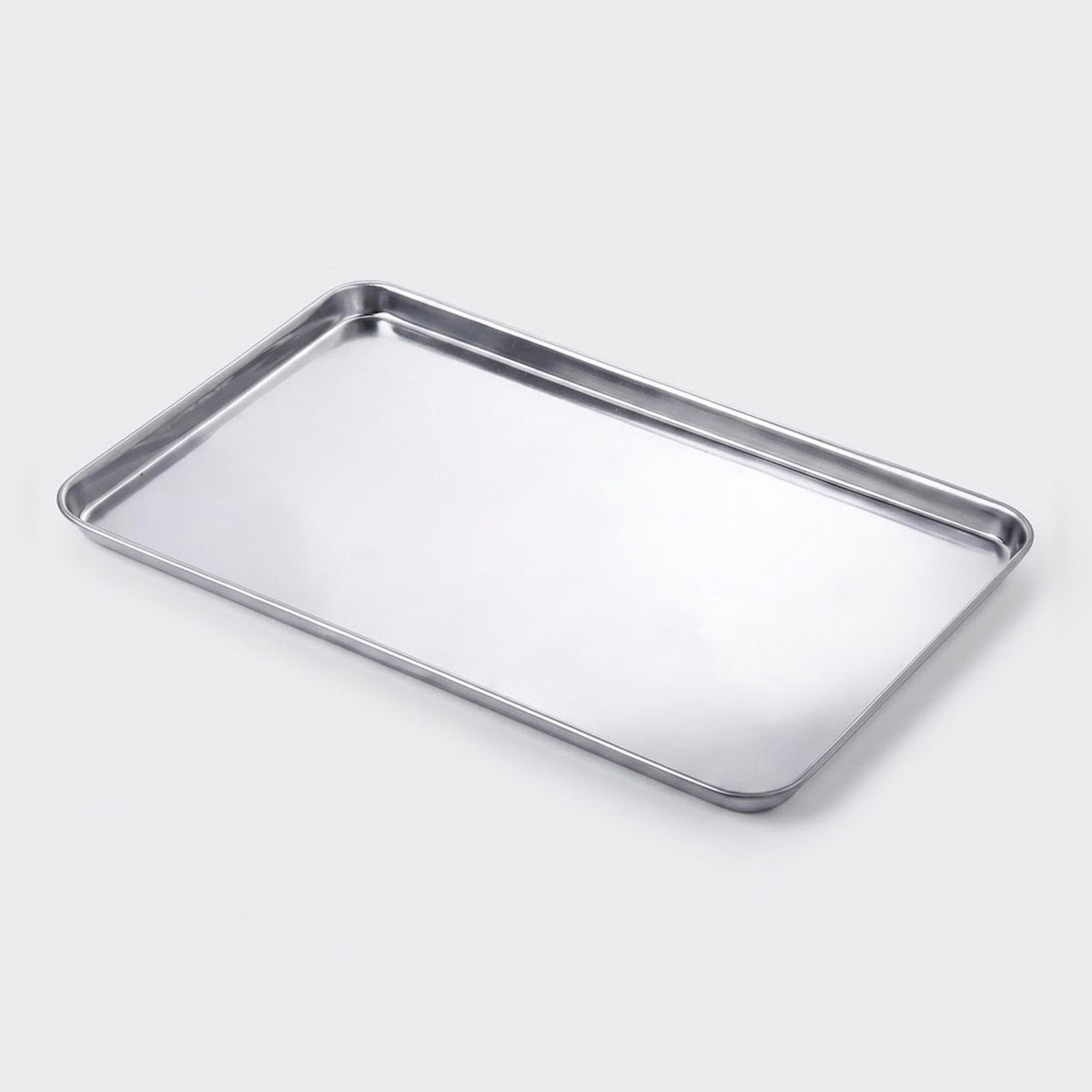 A rectangular stainless steel baking tray with raised edges, shown at an angle on a light gray background.