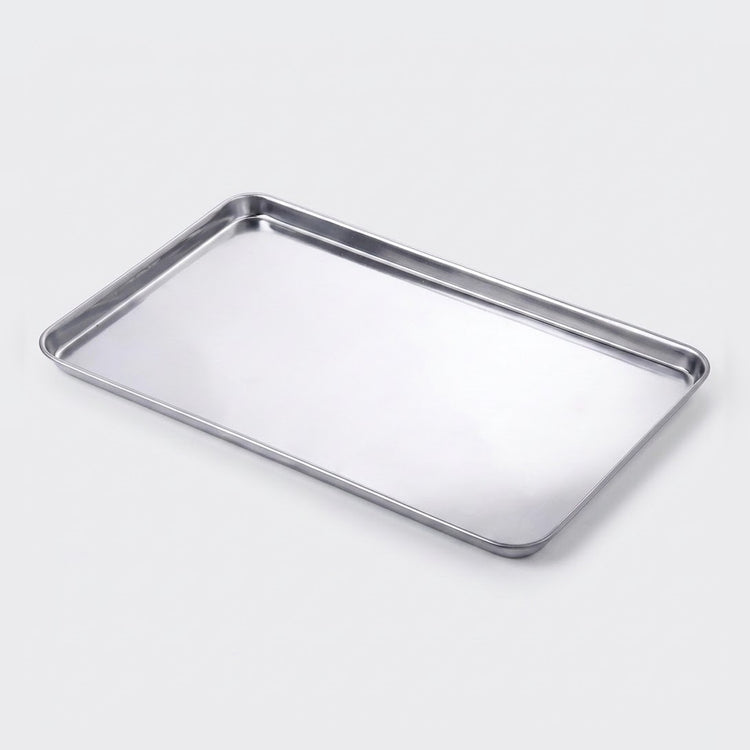 A rectangular stainless steel baking tray with raised edges, shown at an angle on a light gray background.
