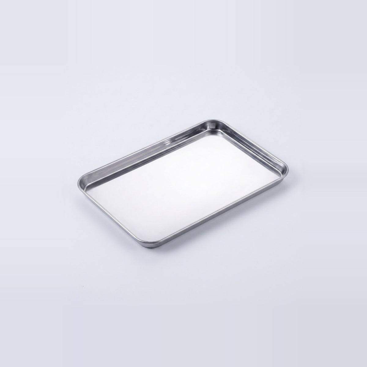 A rectangular stainless steel tray with raised edges, photographed on a clean light gray studio background.