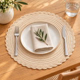 Beige round woven placemat under a plate and cutlery on a wood kitchen table.