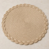 Beige round woven placemat highlights its concentric braid and scalloped braided edge.