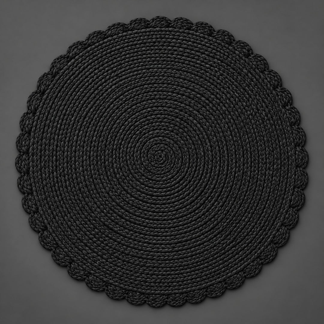 Single black round woven placemat with braided edge on a light gray backdrop.