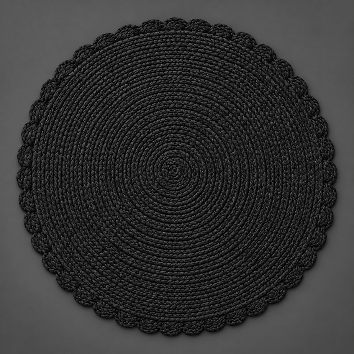 Single black round woven placemat with braided edge on a light gray backdrop.