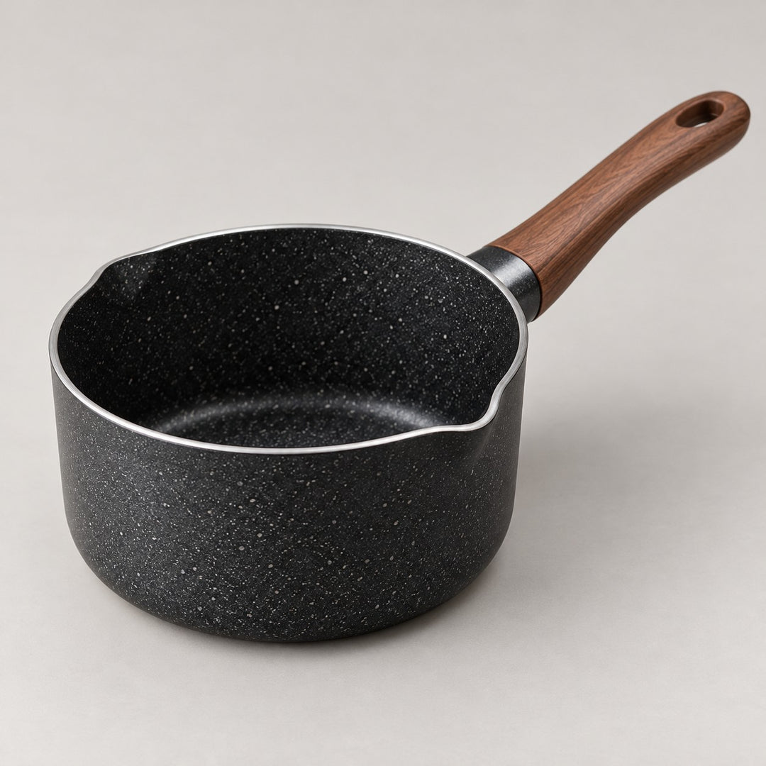 Nonstick saucepan with pour spout and wooden handle shown clearly against a soft studio backdrop.