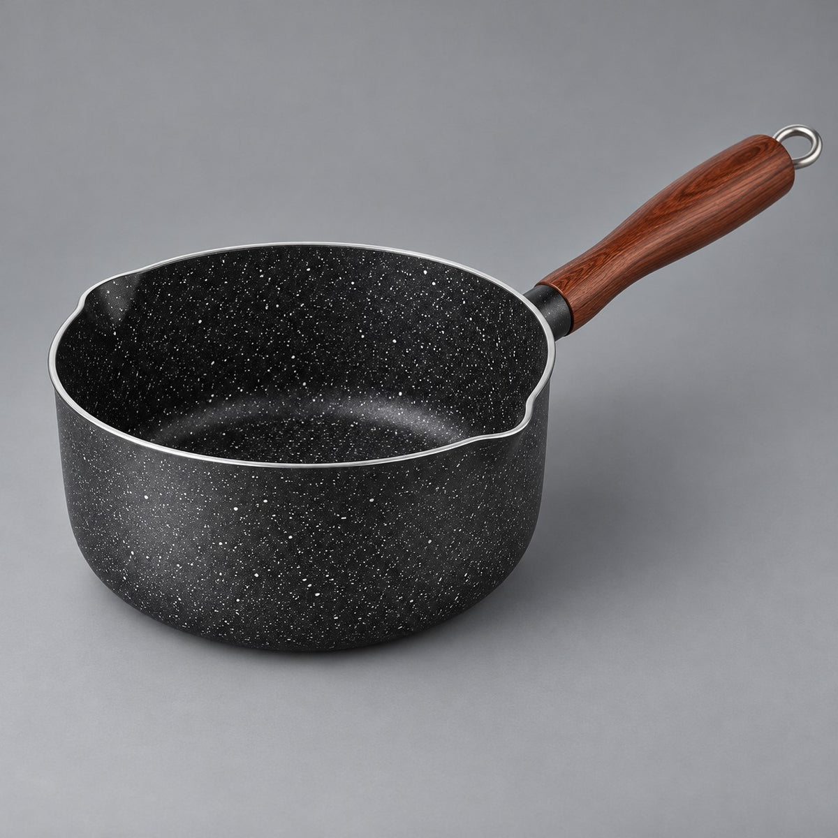 Speckled nonstick saucepan with wooden handle and pour lips shown alone on a pale backdrop.