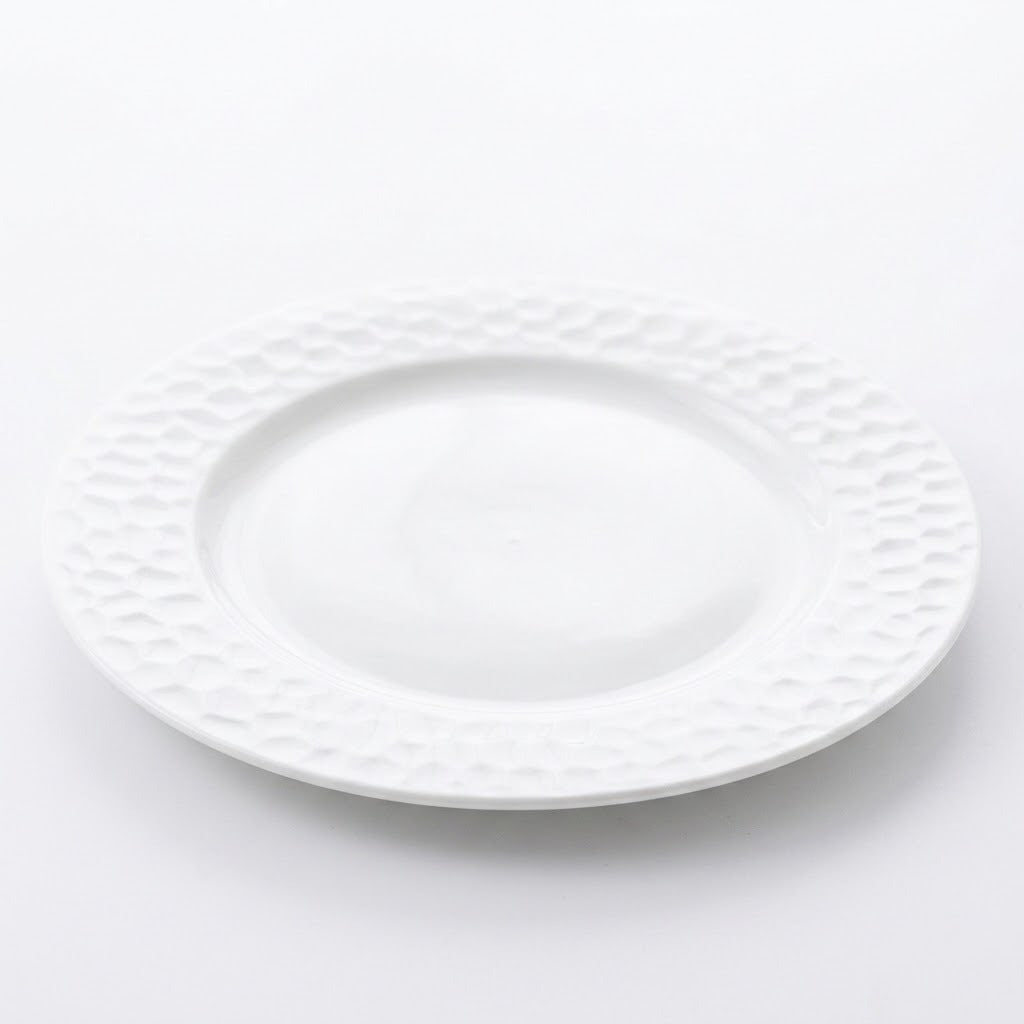 A white ceramic plate with a textured, dimpled pattern around the rim, shown on a clean white background.