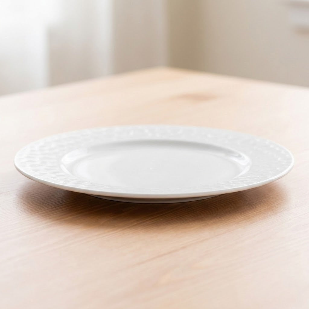 A white ceramic plate with a textured beaded border, resting on a light-colored wooden table.