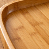 Close-up of the bamboo and wood serving tray's polished honey-colored grain and smooth inner rim.