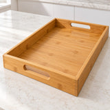 Bamboo and wood serving tray shows its built-in oval handles and raised rim on a kitchen counter.