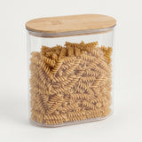 A clear plastic canister with a rounded rectangular shape, filled with rotini pasta, and topped with a light natural wood lid, set against a plain white background.