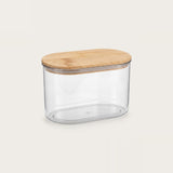 A clear plastic storage container with an oval-shaped light wood lid, shown on a solid light beige background.