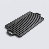 A rectangular black cast iron griddle plate with two side handles, shown at an angle on a light gray background.