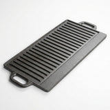 A rectangular black cast iron griddle with ridged cooking surfaces and two loop handles, photographed on a clean white background.