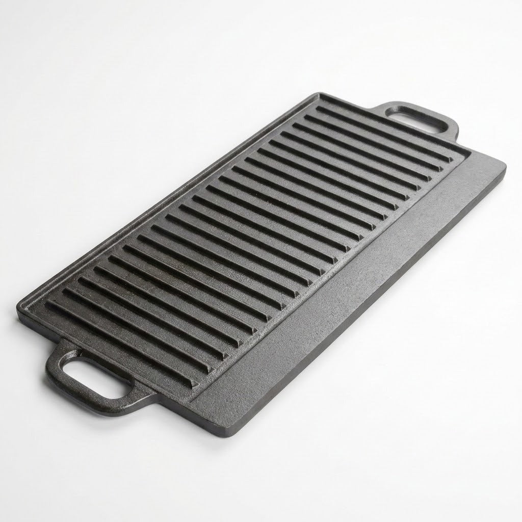 A rectangular black cast iron griddle with ridged cooking surfaces and two loop handles, photographed on a clean white background.