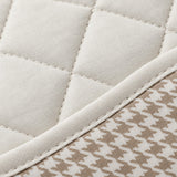 Close-up of off-white polyester quilting, stitching and houndstooth fabric texture.