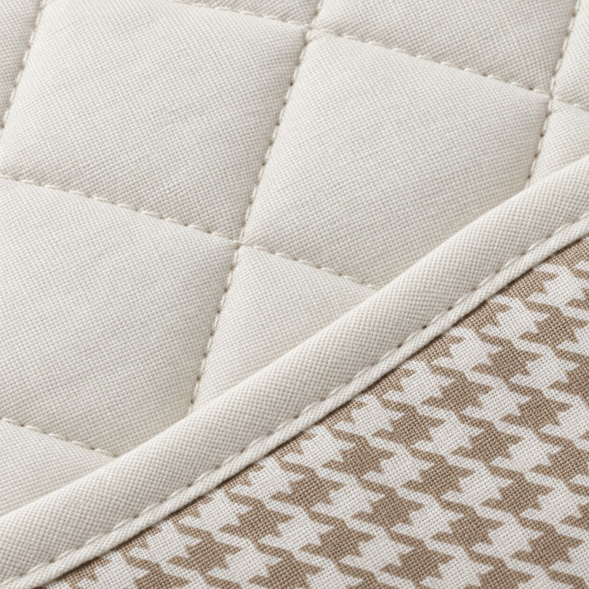 Close-up of off-white polyester quilting, stitching and houndstooth fabric texture.