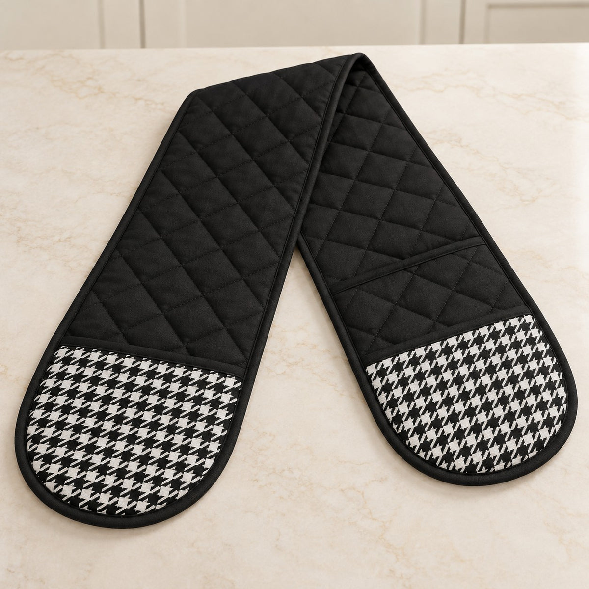 Black houndstooth double oven mitt displayed open to show its connected two-pocket design.