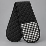 Black quilted houndstooth double oven mitt centered on a pale gray studio background.