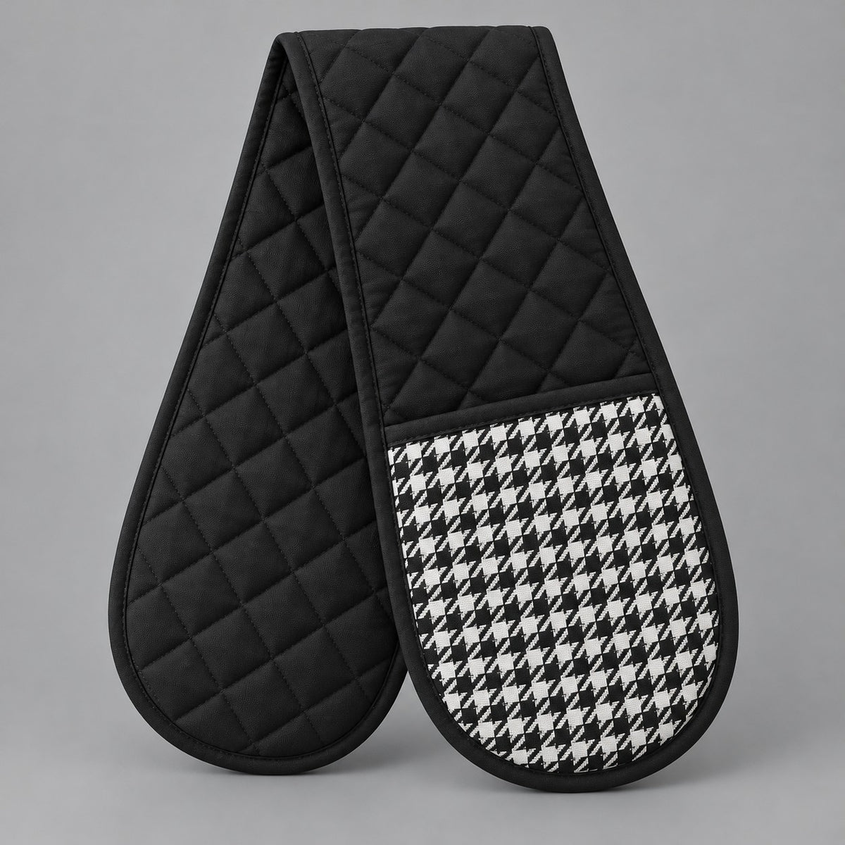 Black quilted houndstooth double oven mitt centered on a pale gray studio background.