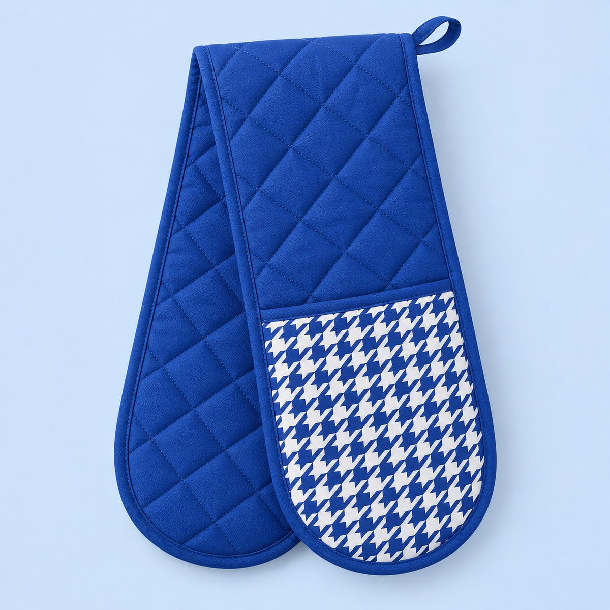 Royal blue quilted houndstooth double oven mitt centered on a pale blue studio background.