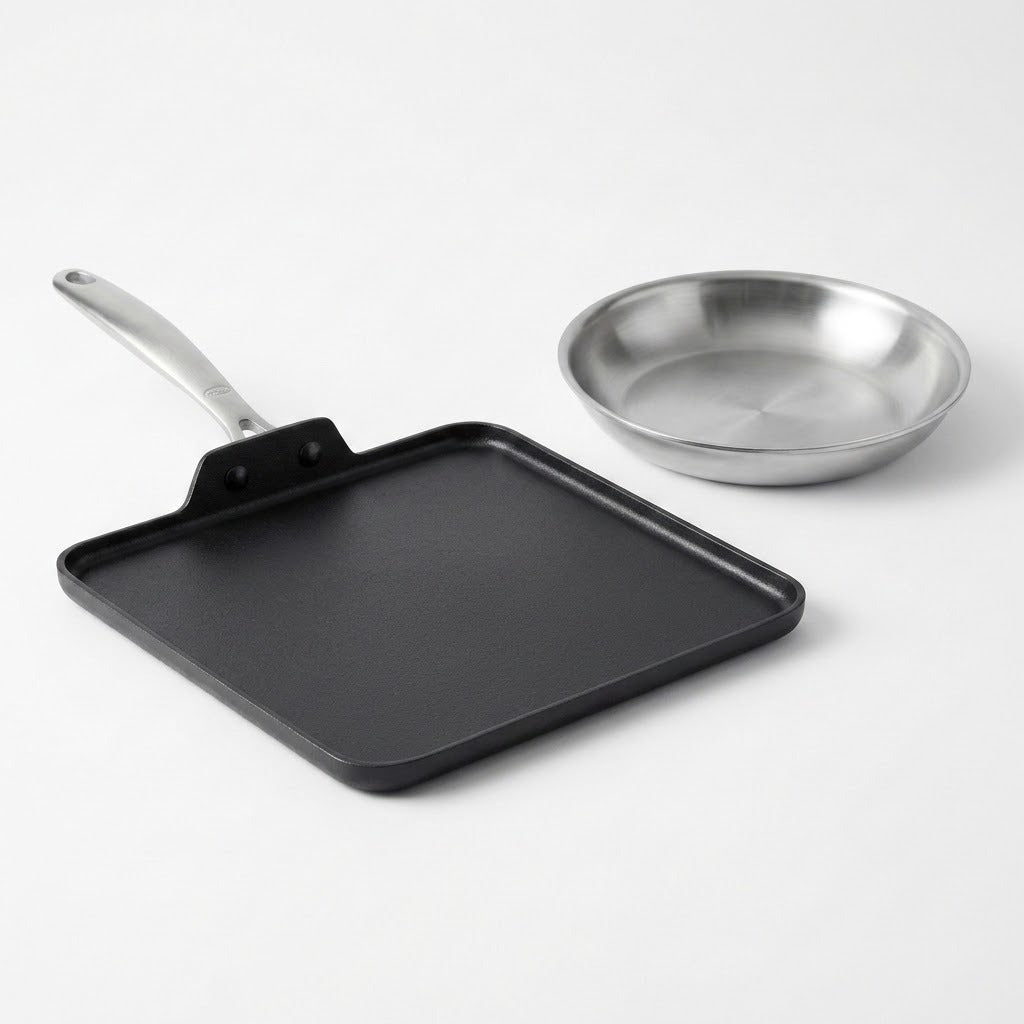 A square black non-stick griddle with a long handle and a small stainless steel frying pan, photographed on a clean white background.