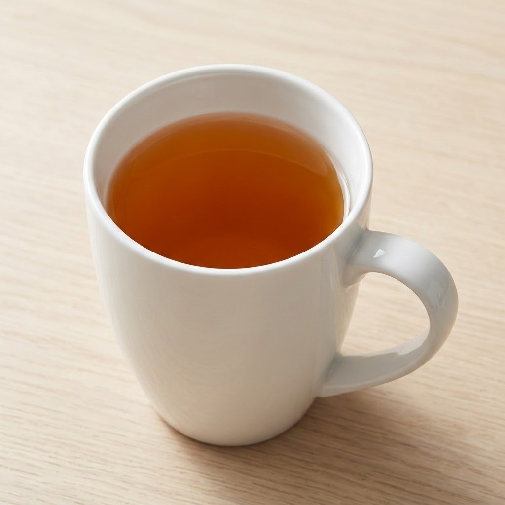 A white ceramic mug filled with amber tea, placed on a light wood tabletop.