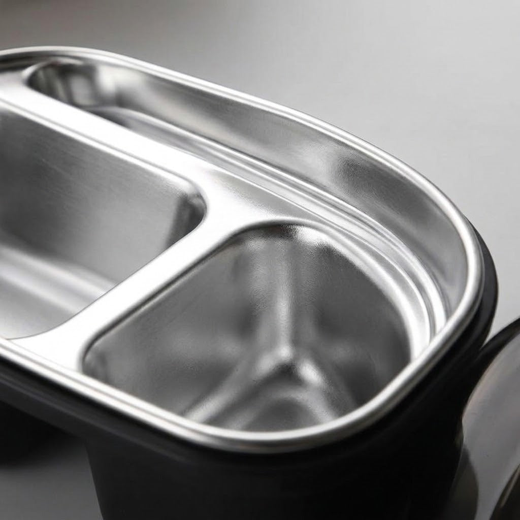 Close-up of a stainless steel three-compartment divided lunch tray with a black outer base, shown on a neutral gray background.